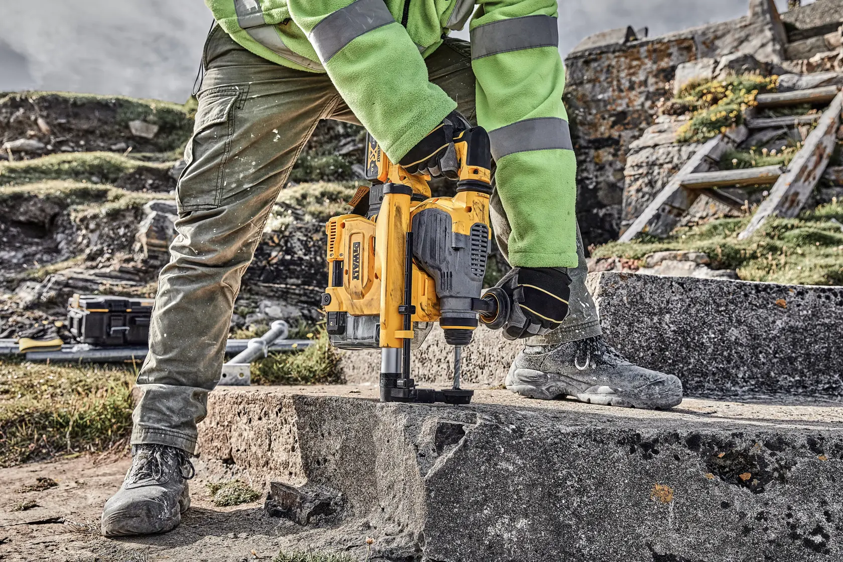 Trabajador usa herramienta DEWALT para taladrar concreto al aire libre.