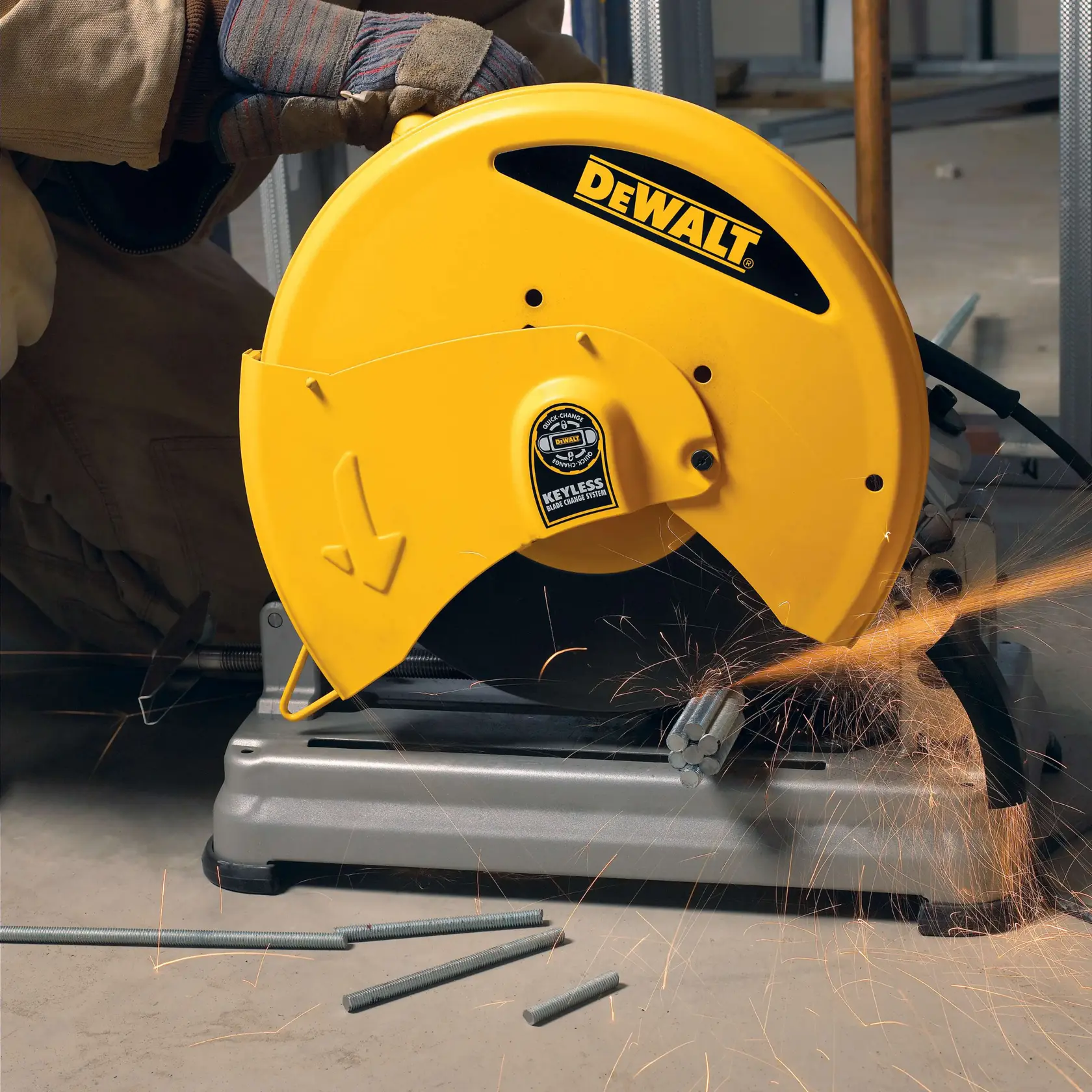 Una sierra de corte de metal amarilla DEWALT D28715 en uso, cortando varillas de metal y generando chispas, operada por una persona que lleva guantes de protección.