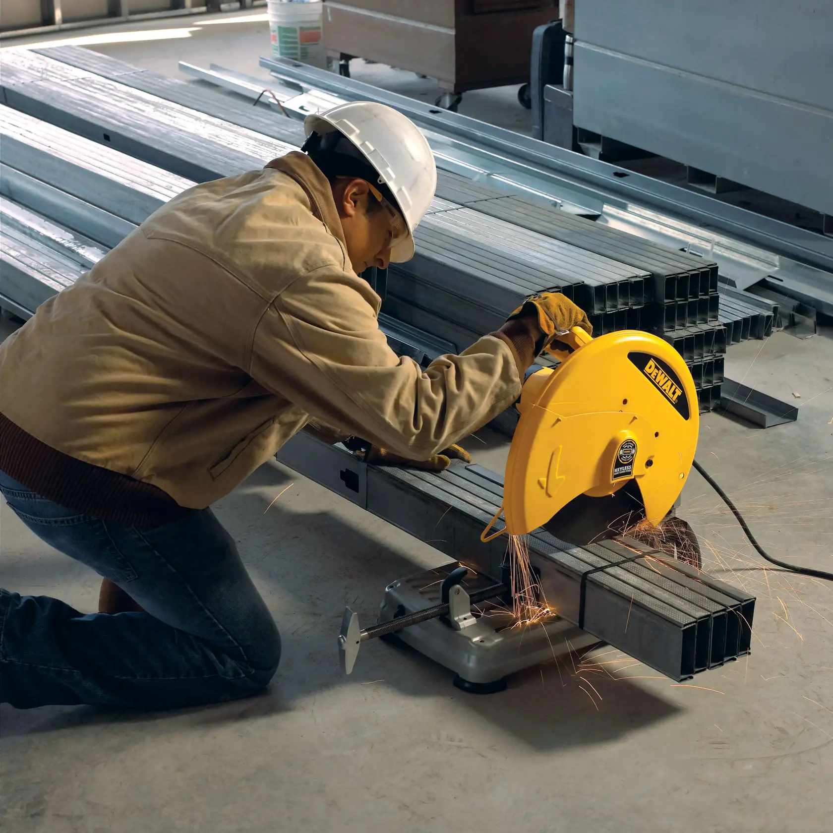 Una persona con equipo de seguridad utiliza una sierra para cortar metal DEWALT para cortar tubos de acero en un entorno industrial. Se pueden ver chispas mientras la sierra está en funcionamiento.