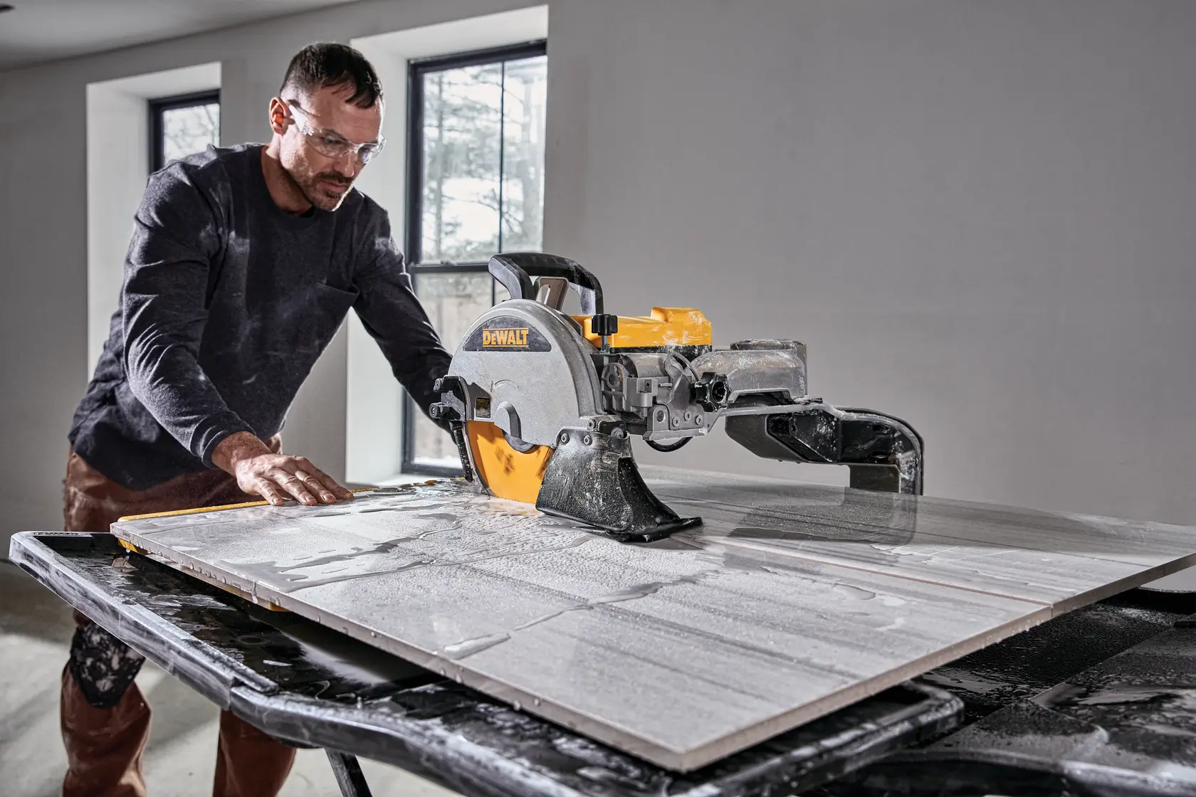 Foto de sierra para azulejos DEWALT, SKUs D36000-QS, D36000. Usuario cortando azulejo en mesa mojada.