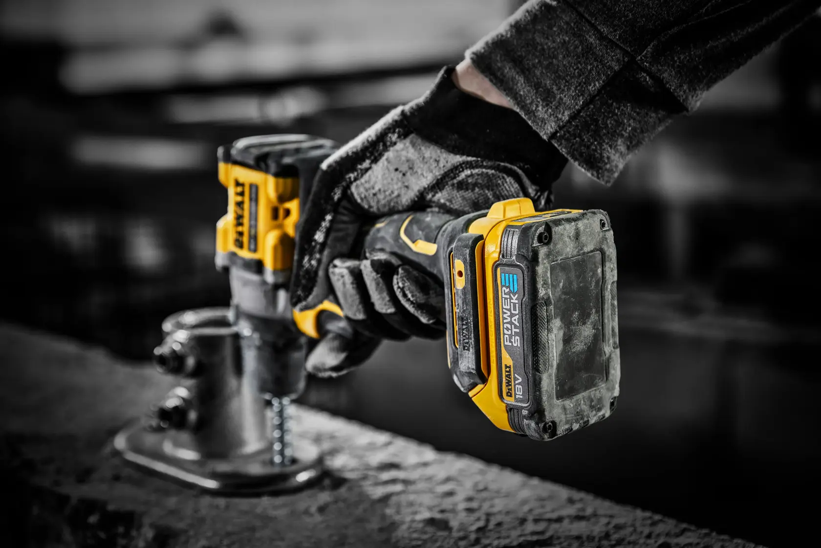 Batería DEWALT Powerstack 18V en taladro inalámbrico, usada por mano enguantada en obra.