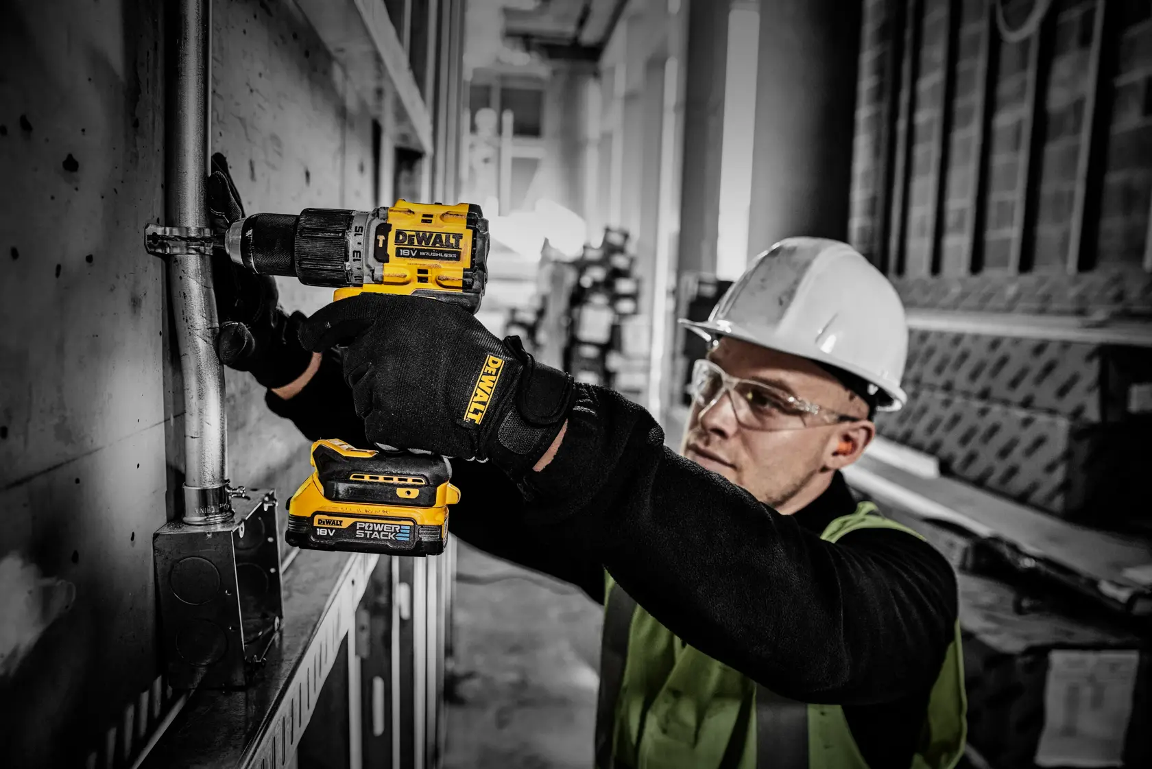 Trabajador utiliza batería DEWALT Powerstack en taladro inalámbrico durante instalación eléctrica.