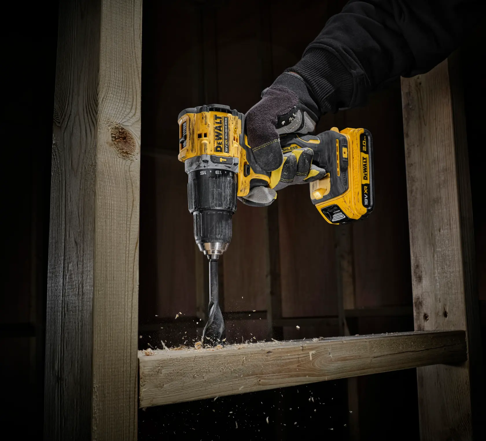 Taladro inalámbrico DEWALT perfora madera y vuela aserrín. El trabajador lleva guantes.