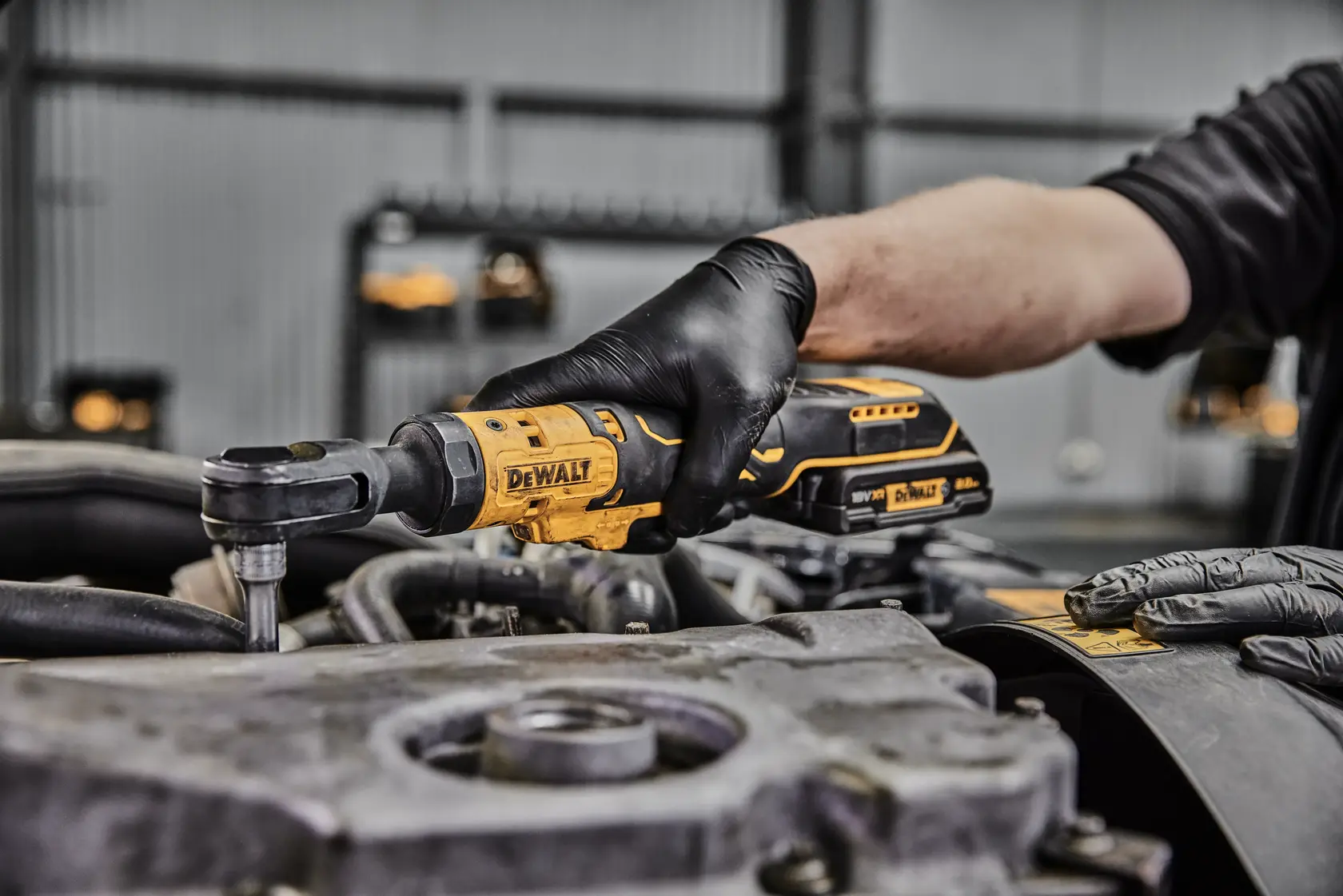 Foto de herramienta DEWALT de carraca DCF512N-XJ, DCF512N en uso en motor, usuario con guantes negros.