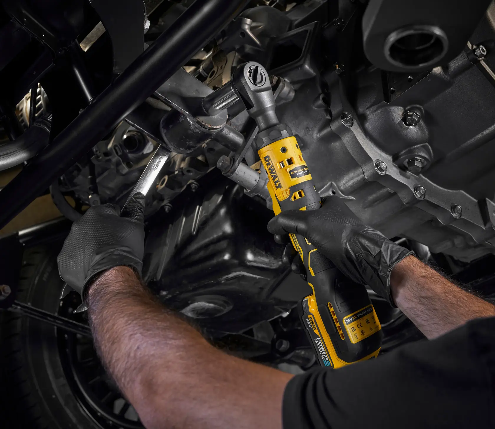 Foto DEWALT DCF512N-XJ, DCF512N carraca inalámbrica usada en motor, usuario con guantes.