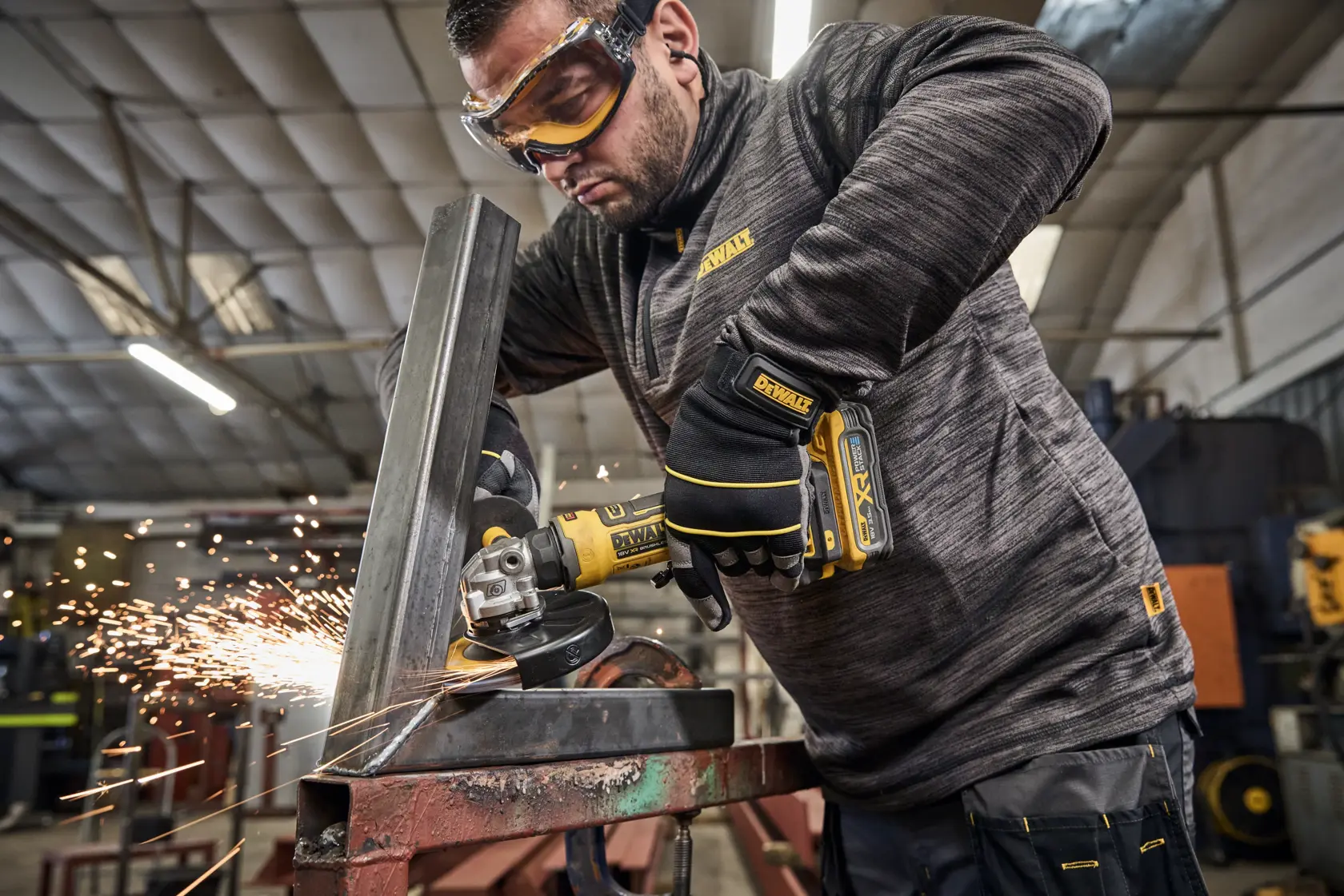 Amoladora DEWALT cortando metal y generando chispas. Operario con guantes en taller industrial.