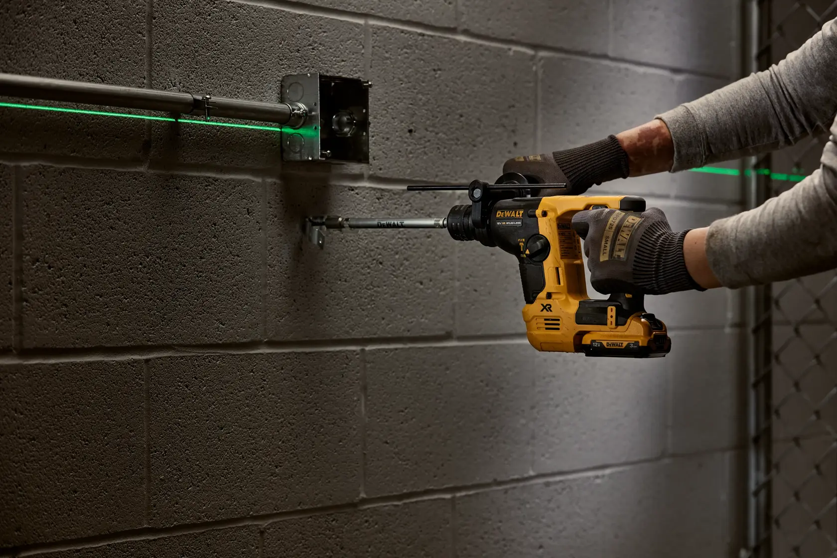 Persona utiliza taladro DEWALT inalámbrico debajo de un fregadero para reparar tuberías junto a una pared.