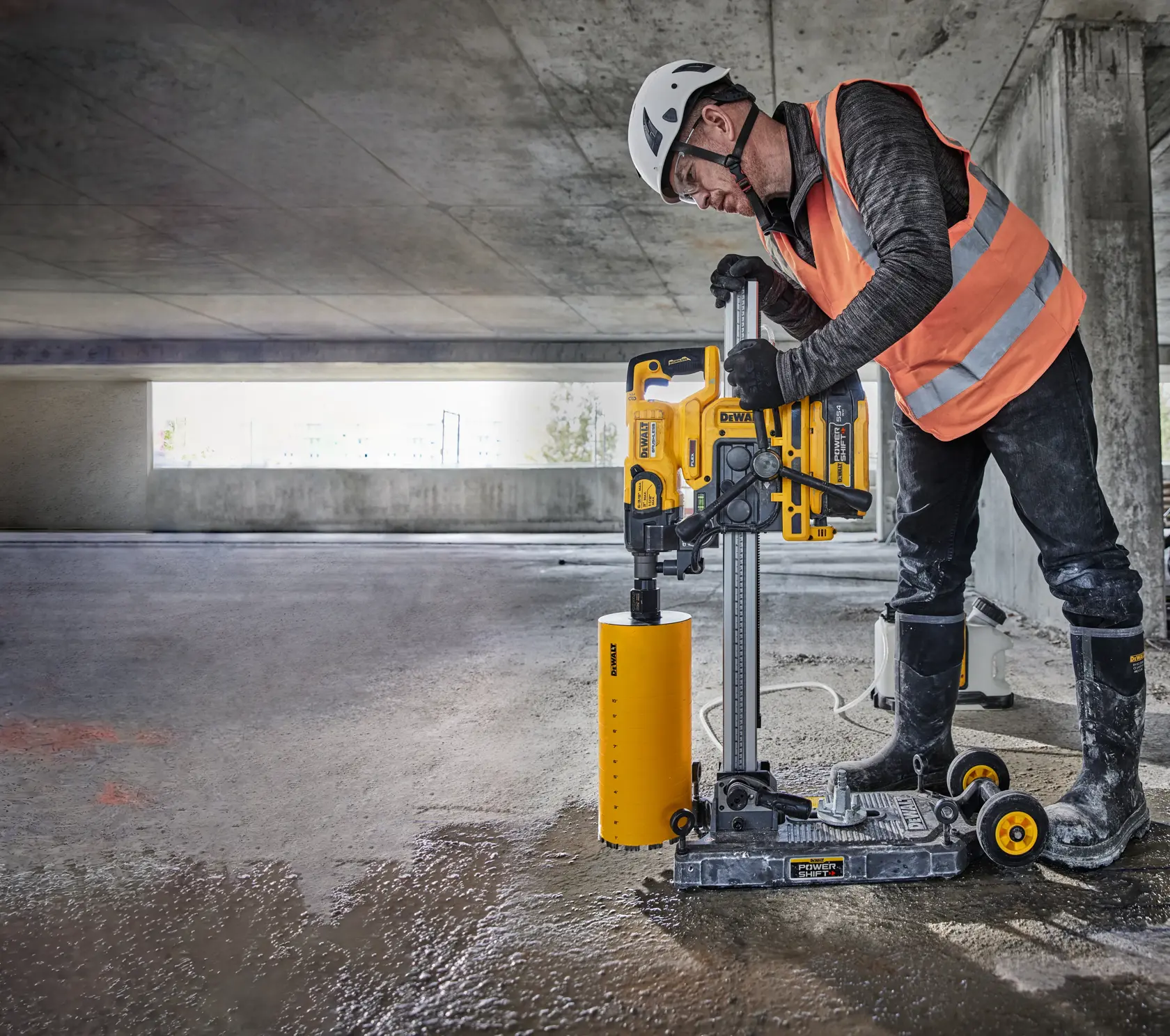 Vista de primer plano de un taladro de núcleo DEWALT modelo DCPS151 montado en un riel vertical, destacando sus controles de usuario reflejados y el mecanismo de bloqueo. El texto superpuesto dice « CONTROLES DE USUARIO REFLEJADOS - BLOQUEE EL TALADRO DE NÚCLEO EN SU LUGAR ».