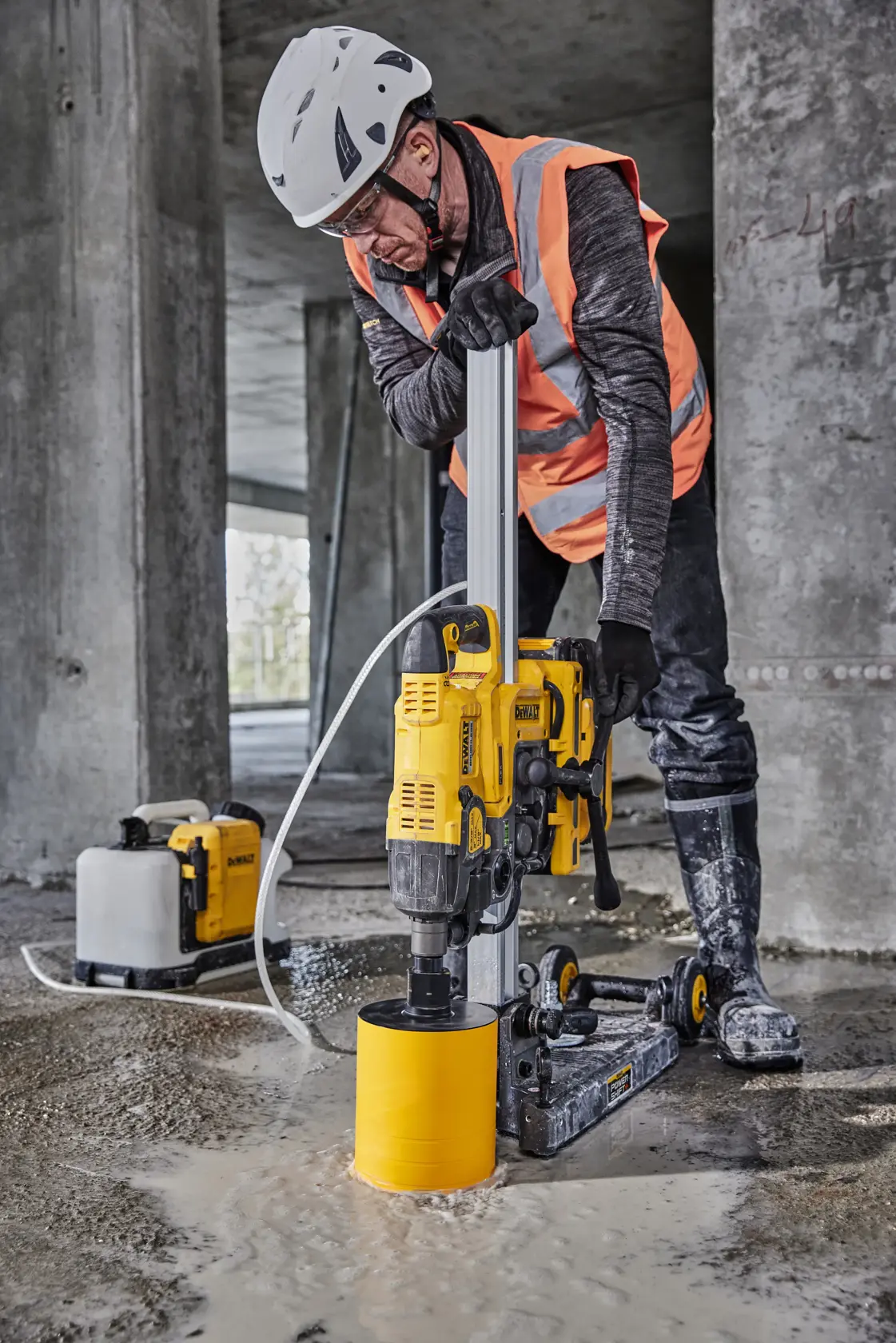 Un trabajador con equipo de seguridad, incluyendo casco y chaleco de alta visibilidad, utiliza una herramienta inalámbrica DEWALT para cortar o recortar equipo en un sitio de construcción. Se ven cajas y herramientas eléctricas DEWALT en el área de trabajo.