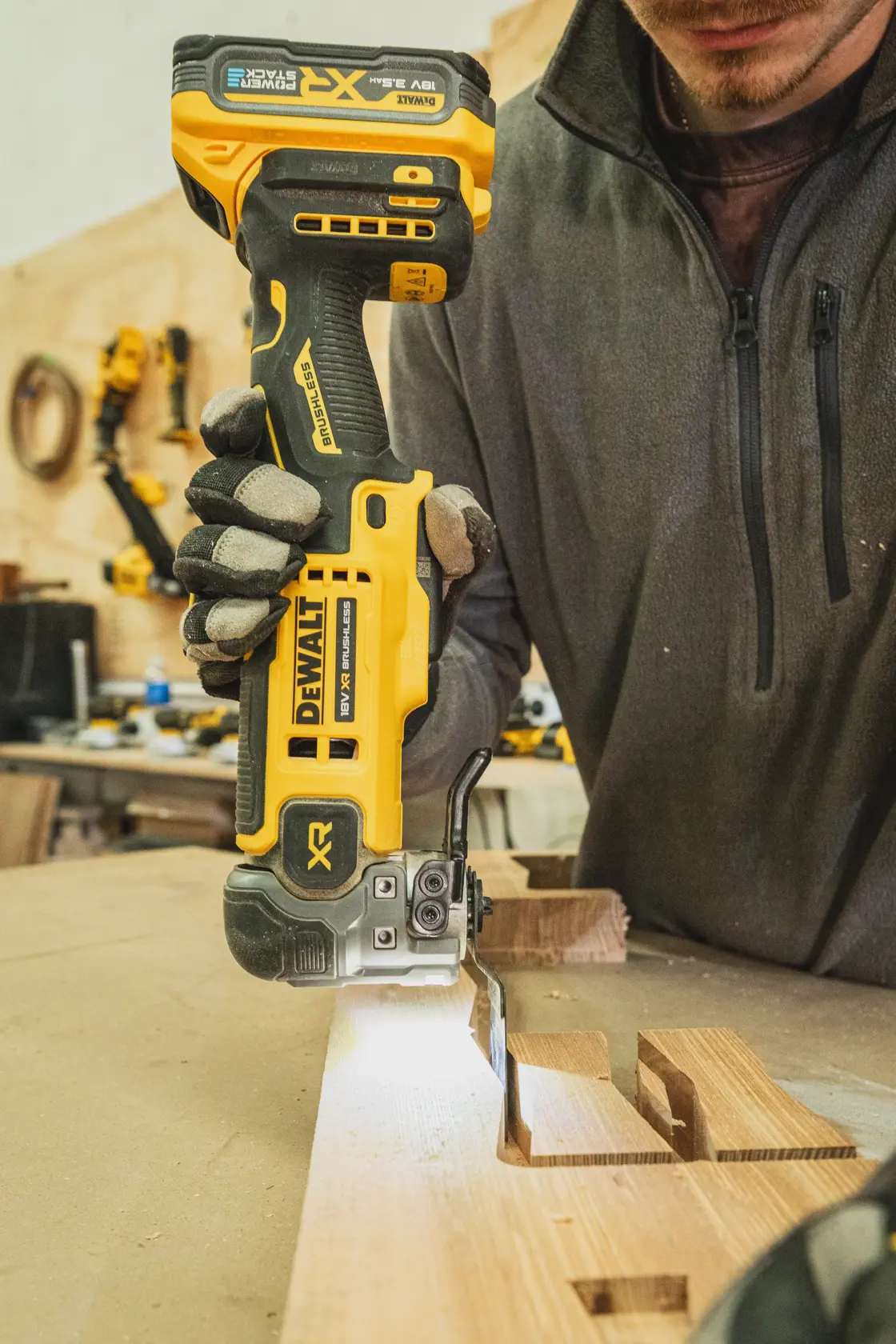 Persona usando una sierra de calar inalámbrica DEWALT para cortar madera en el taller.