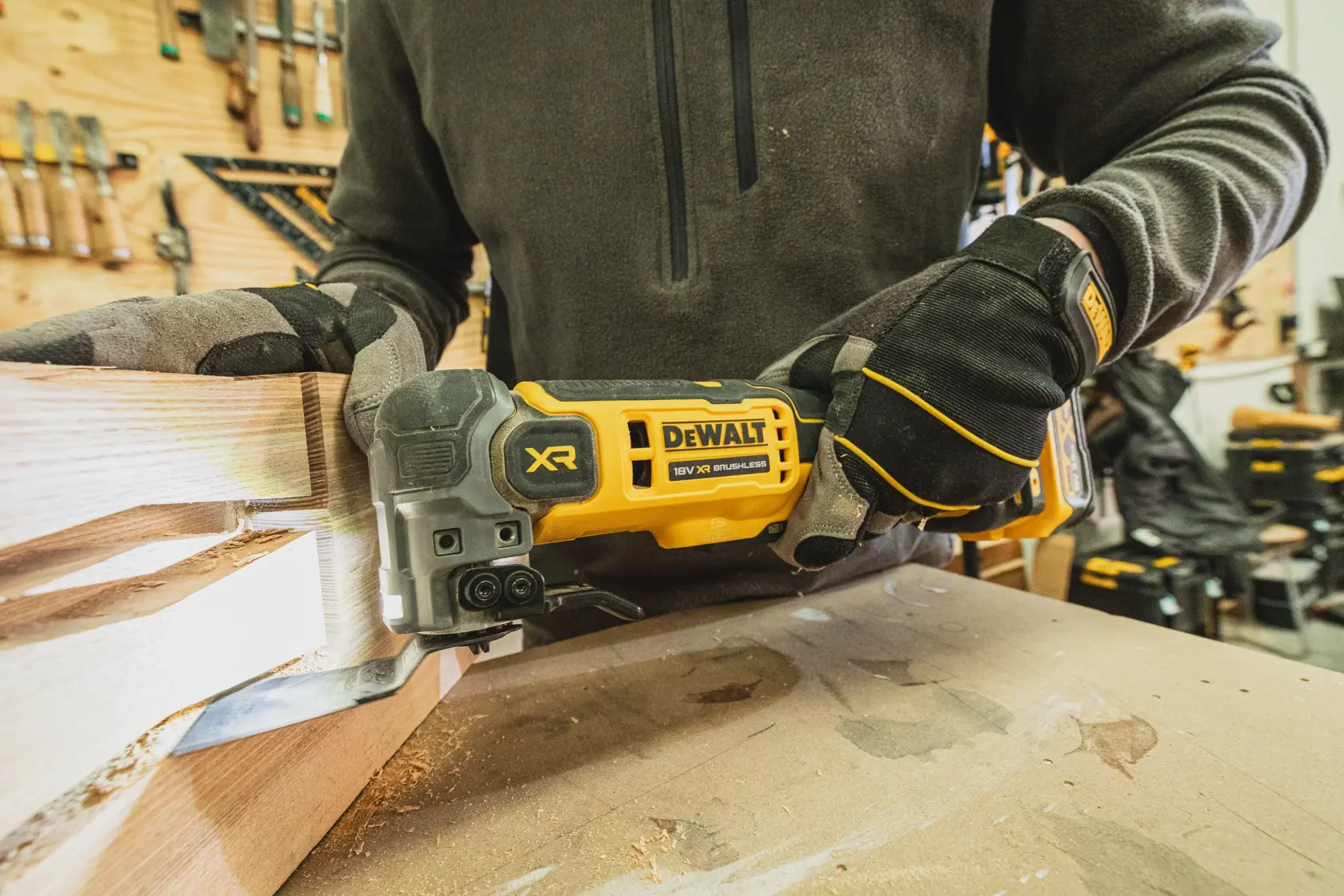 Persona usa herramienta DEWALT XR sin escobillas para cortar madera, con guantes en taller.