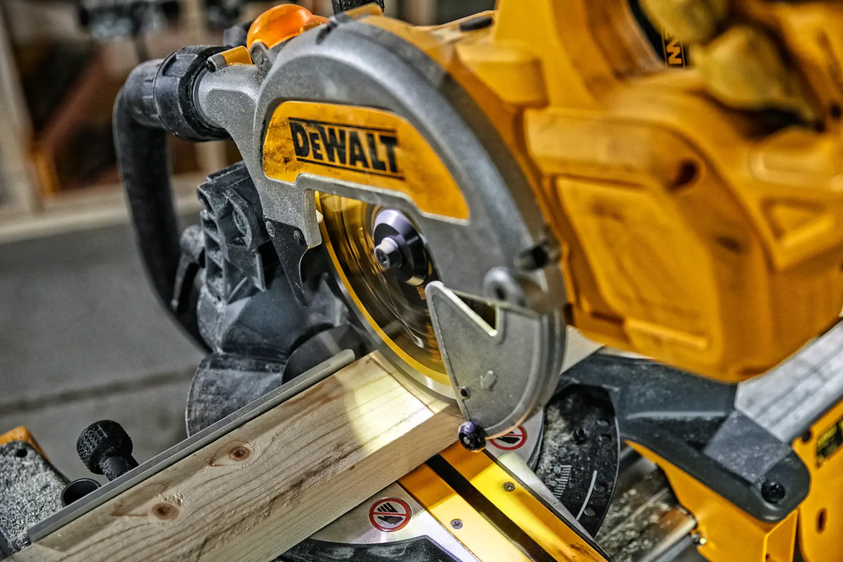 Sierra ingletadora DEWALT cortando madera en taller. Primer plano de la herramienta en uso.