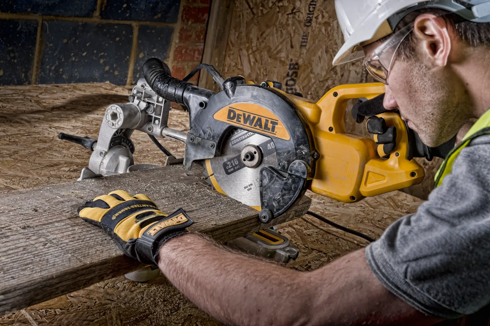 Sierra ingletadora DEWALT corta madera, usada por persona con guantes y casco en obra.