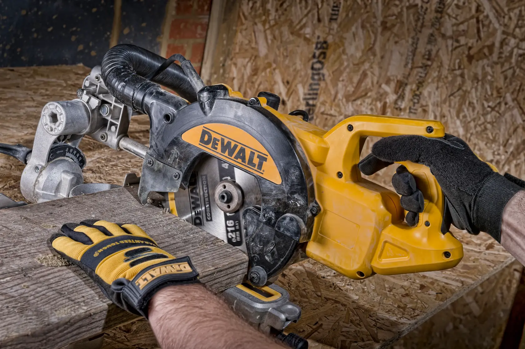 Manos con guantes usan una sierra circular DEWALT para cortar madera sobre el banco de trabajo.