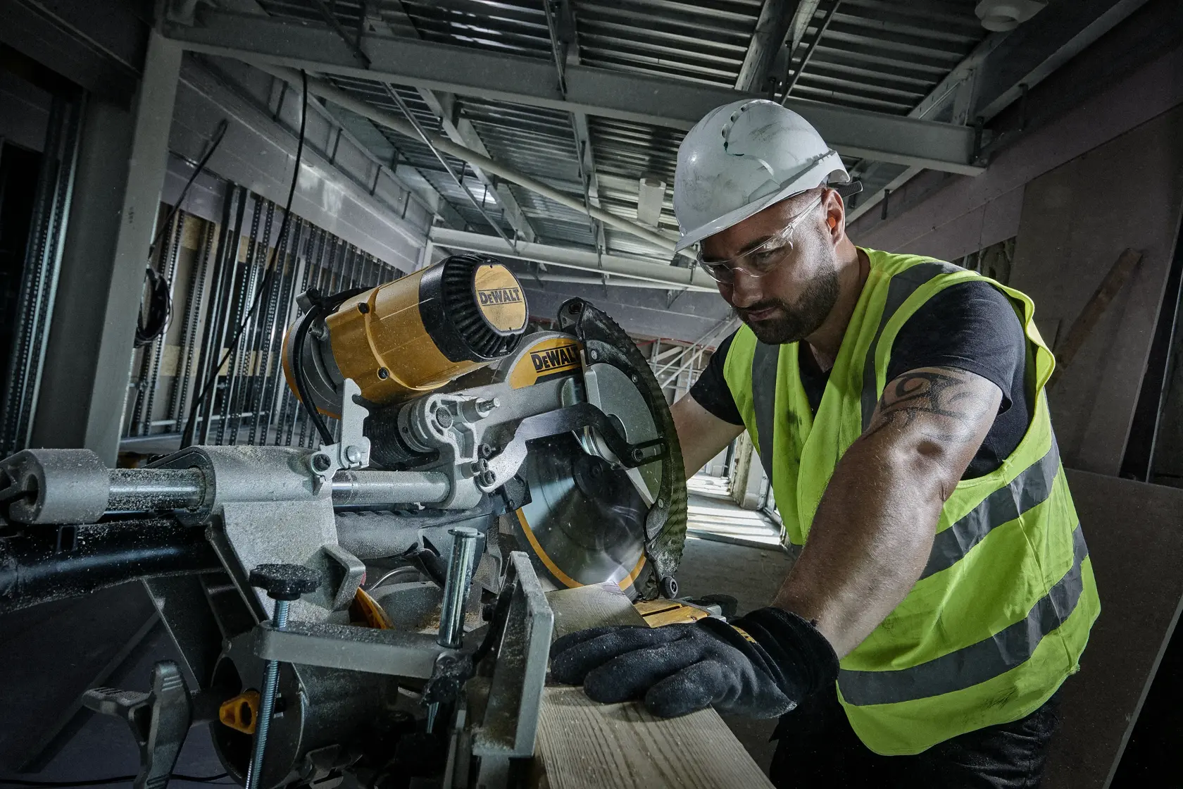 Trabajador corta madera con sierra circular DEWALT en obra, usando chaleco reflectante y equipo de seguridad.