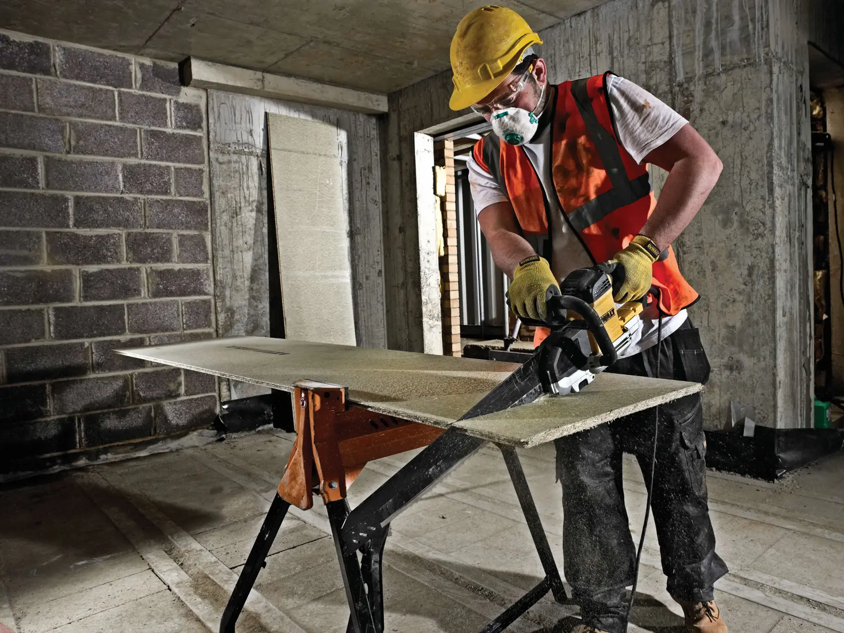 Trabajador corta una tabla con sierra DEWALT en obra, usando equipo de protección.