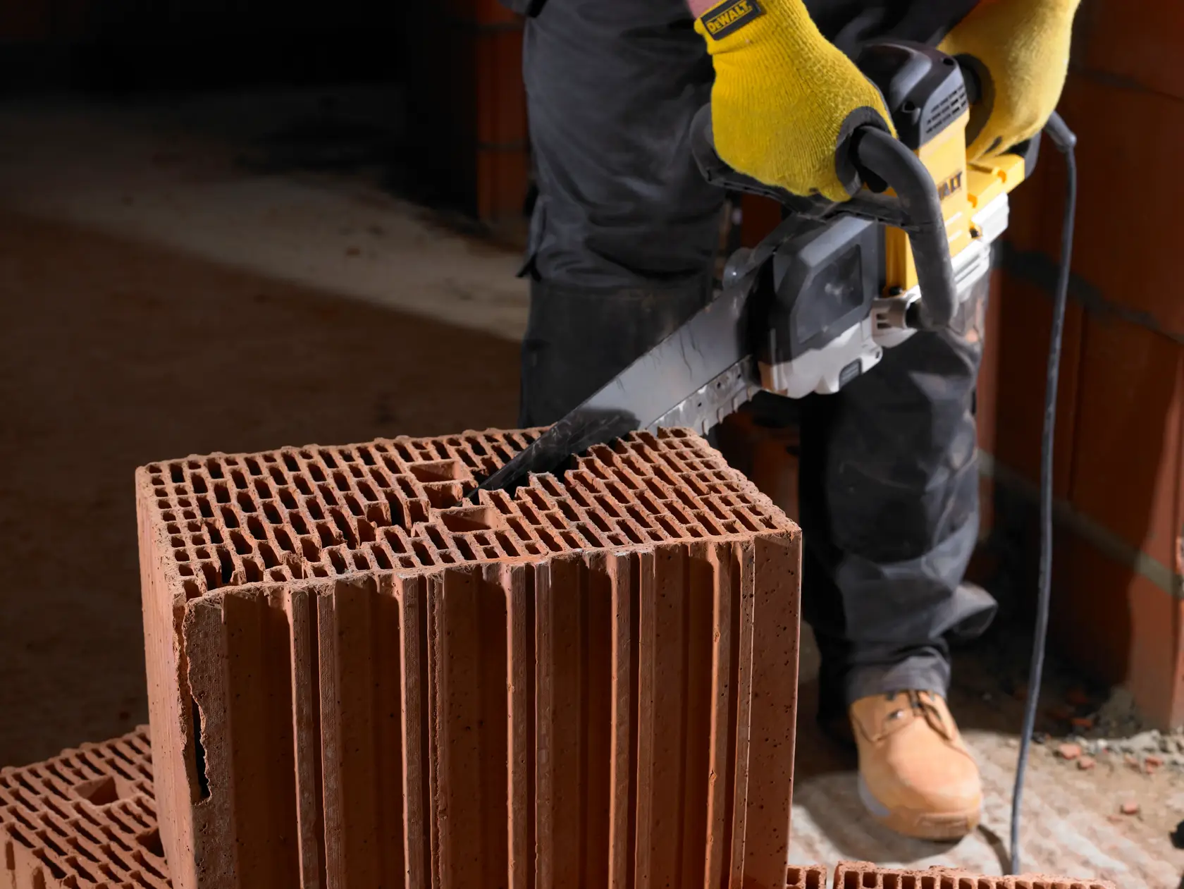 Persona usa sierra DEWALT para cortar ladrillo hueco en obra.