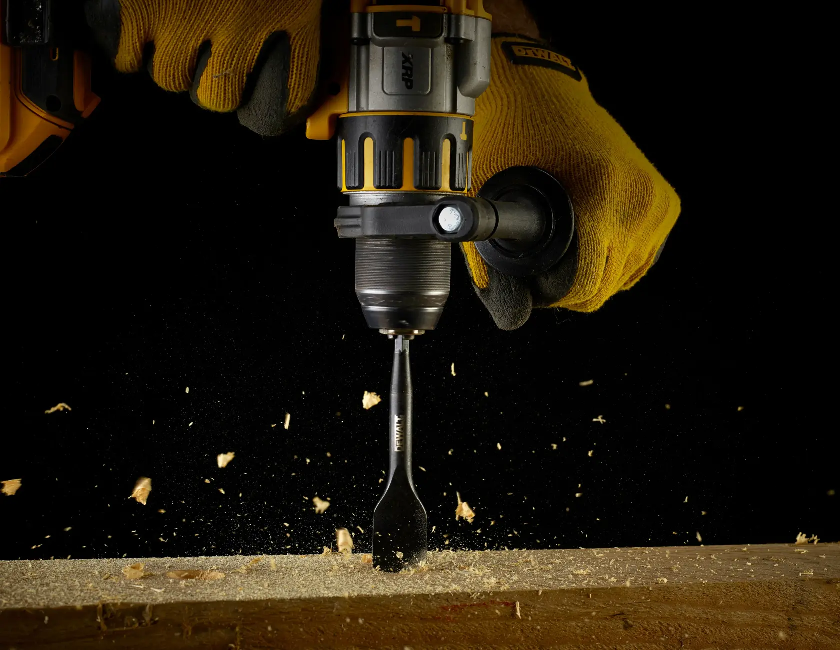 Taladro DEWALT con broca plana DT4765 perforando madera en espacio reducido, sujetado con guantes.
