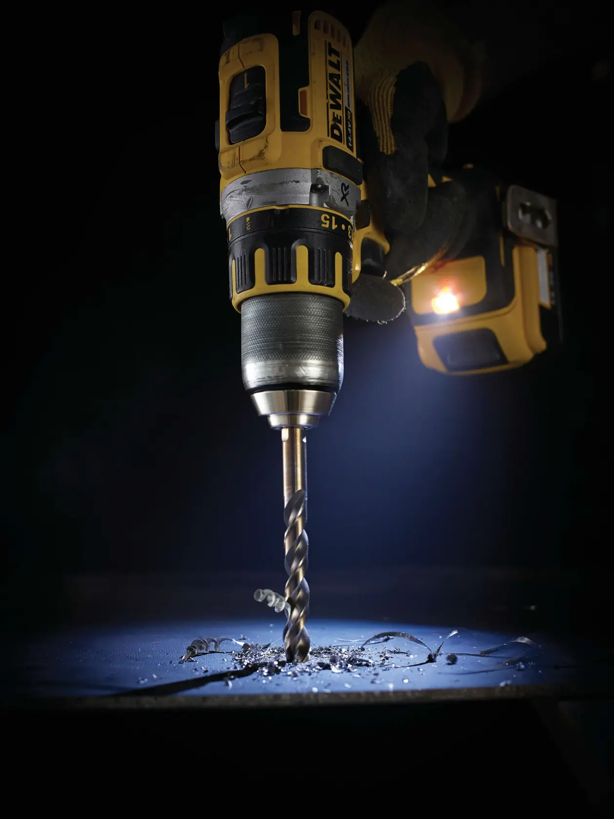 Taladro DEWALT usando DT5057, DT5057-QZ SKUs, perforando metal, fotografía, iluminado en ambiente oscuro.