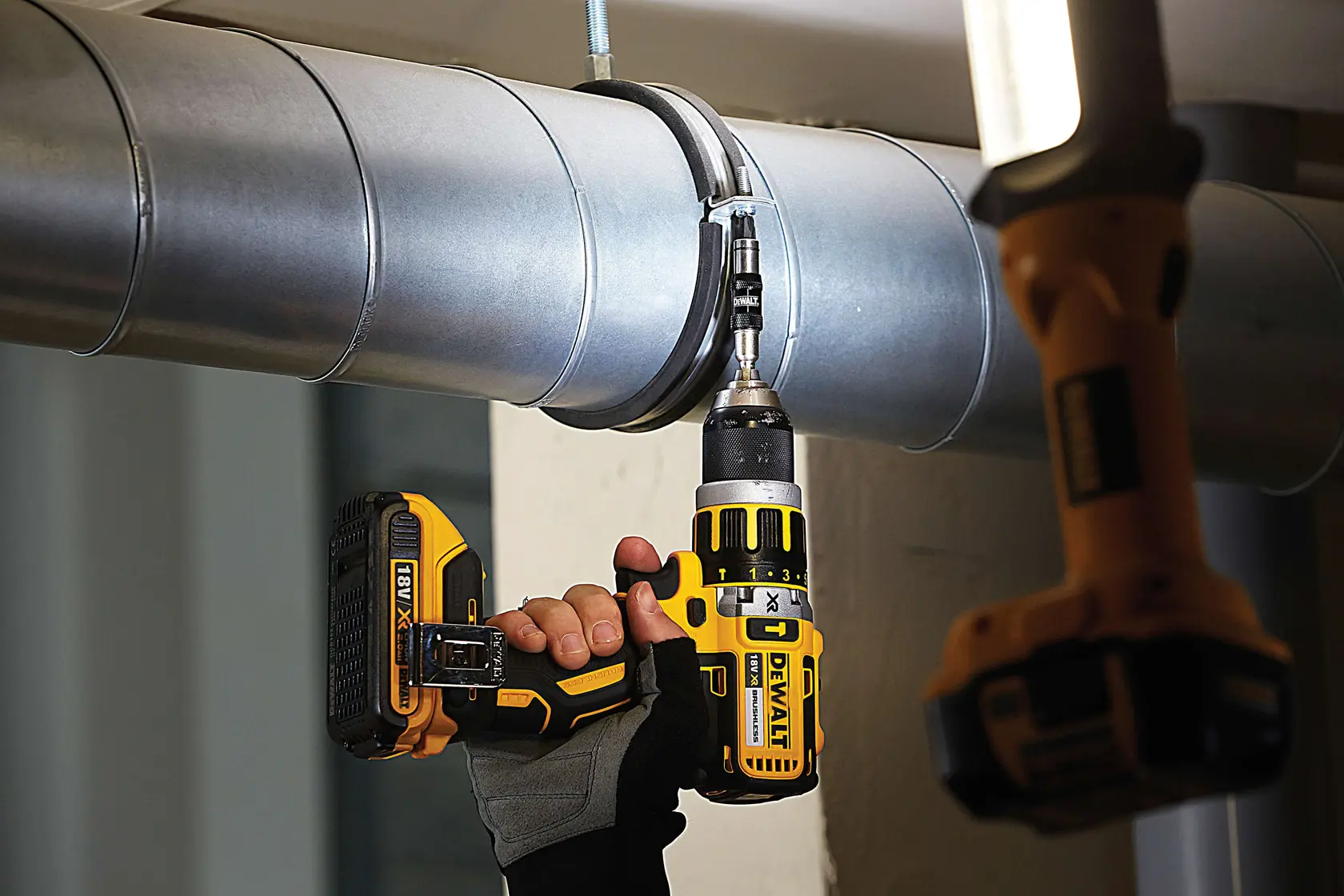 Foto de taladro inalámbrico DEWALT DT70518T usado en conducto metálico por mano enguantada.
