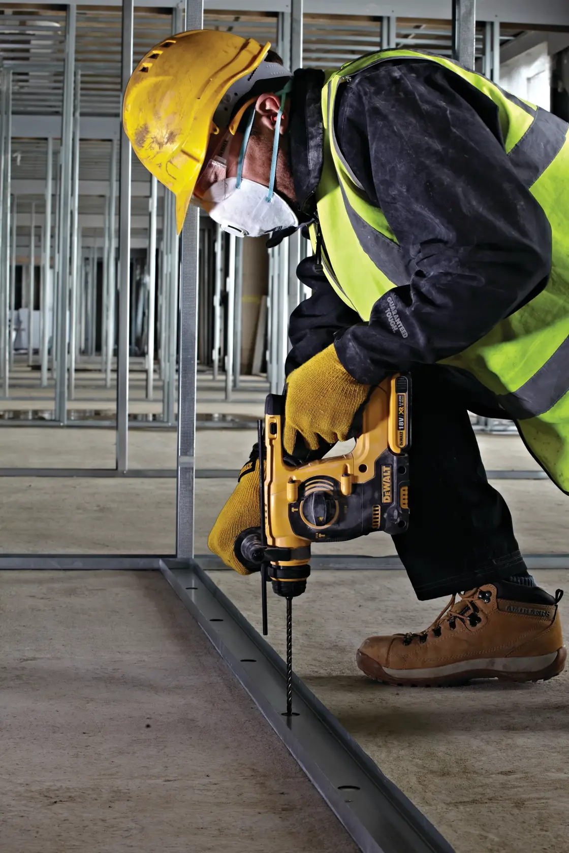 Trabajador con equipo de seguridad usa taladro DEWALT para perforar estructura metálica en obra.