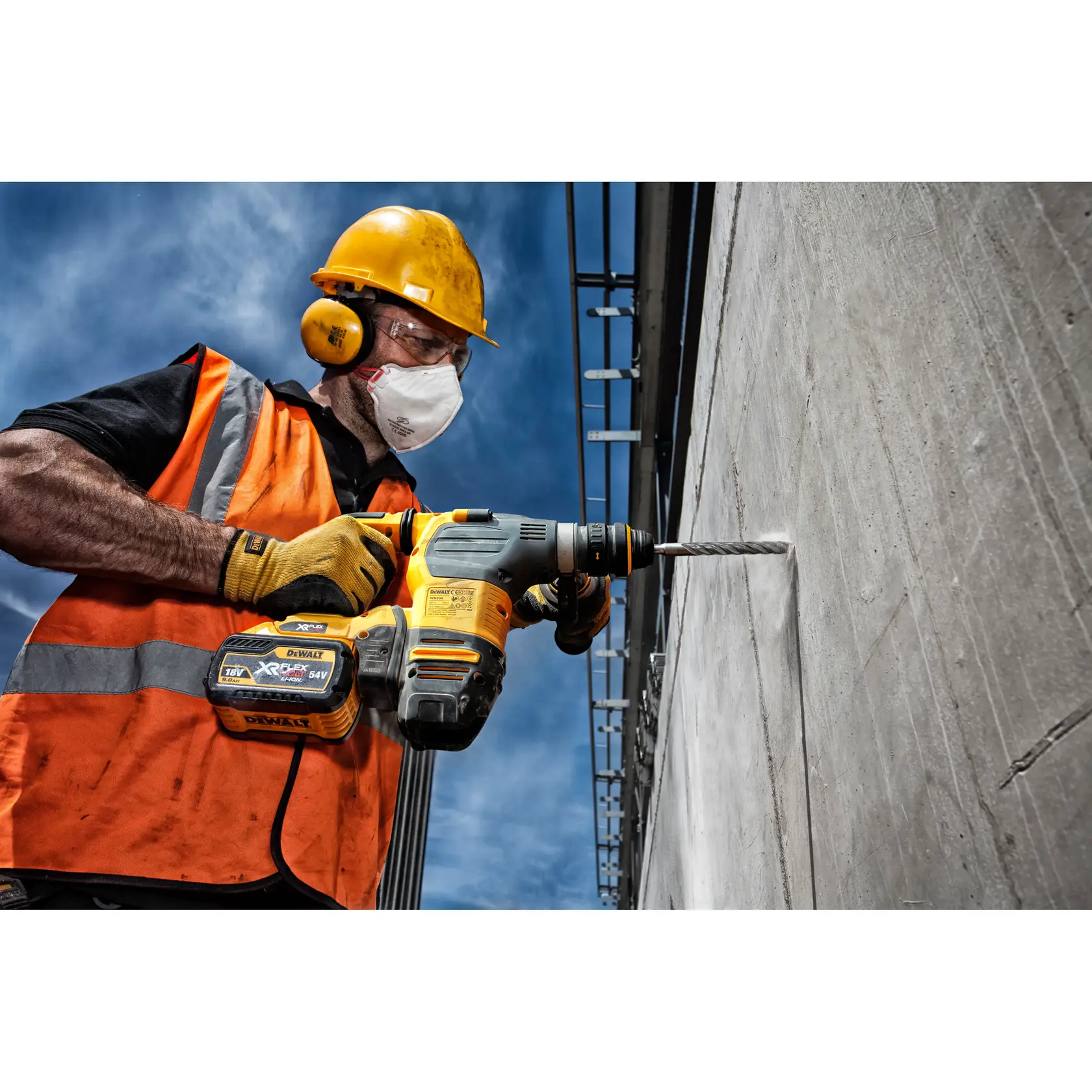Trabajador usa DEWALT DT9545 para perforar un muro de concreto afuera con equipo de seguridad.