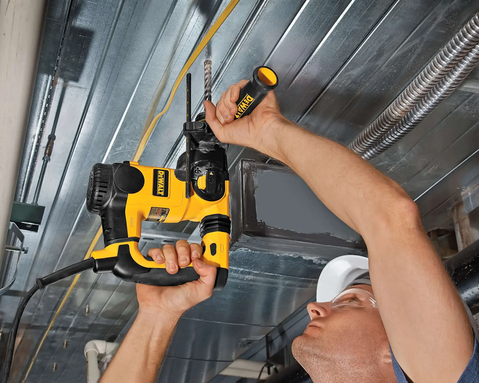 Persona utiliza taladro DEWALT para perforar un techo metálico, se ven la herramienta y los brazos.