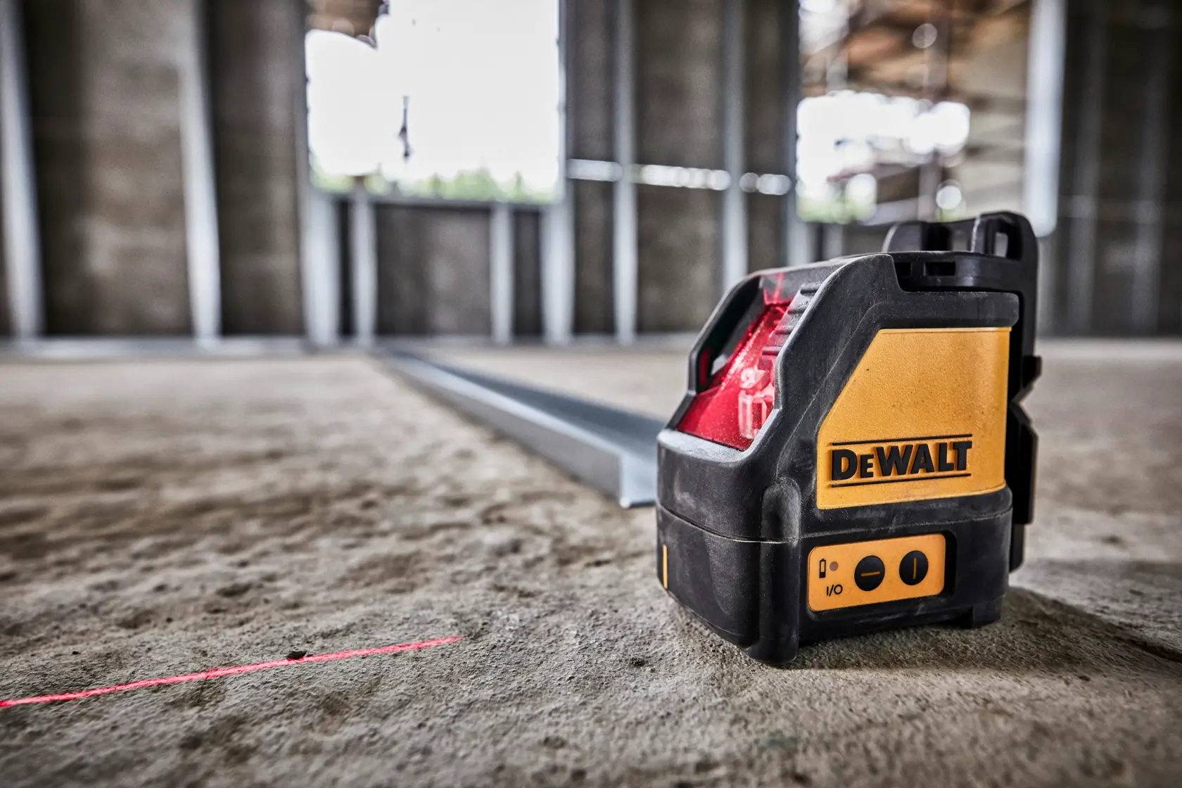 Dewalt DW088K cross line laser level. The device is yellow and black, features control buttons on the front, and has the Dewalt logo on the side. It is housed in a sturdy casing.