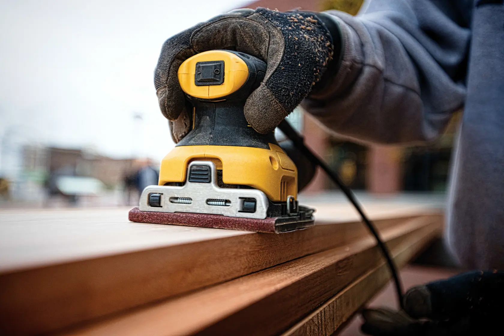 Un kit ponceuse électrique DEWALT. L'image montre une ponceuse jaune et noire DEWALT avec un sac de collecte de poussière, une plaque de ponçage et un sac de transport noir avec le logo DEWALT.