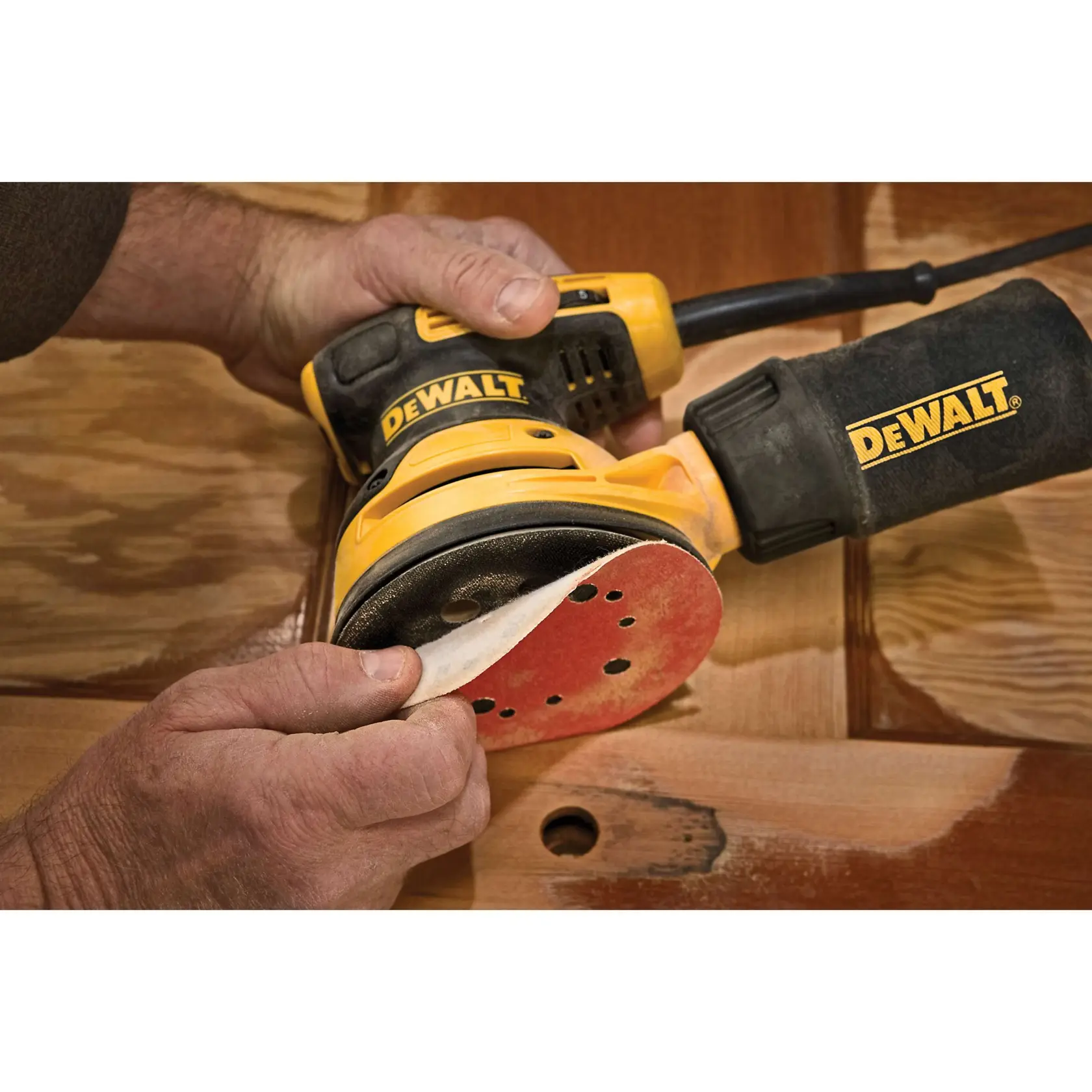 A DEWALT random orbital sander with a dust bag and a black carrying case, all displaying the DEWALT logo.