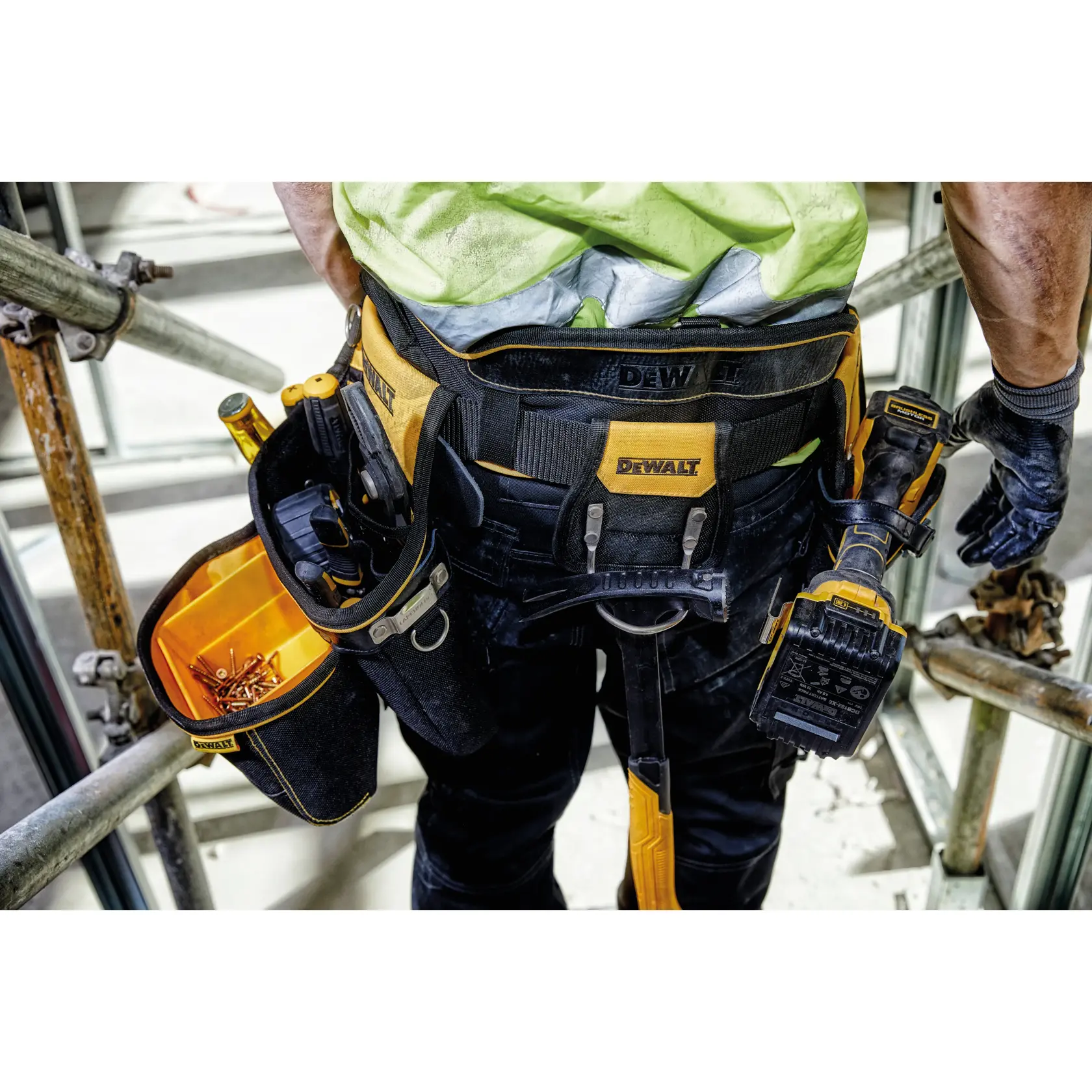 Cinturón de herramientas DEWALT usado por un trabajador con herramientas y tornillos en obra.